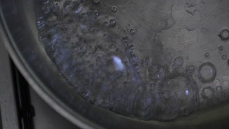 camera captures the process of pouring water into the pan and removing the pan from the gas flame