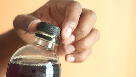 persona abriendo una botella de refresco oscuro