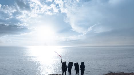 the travelers with fire stick standing on the top of sandy rock near the sea