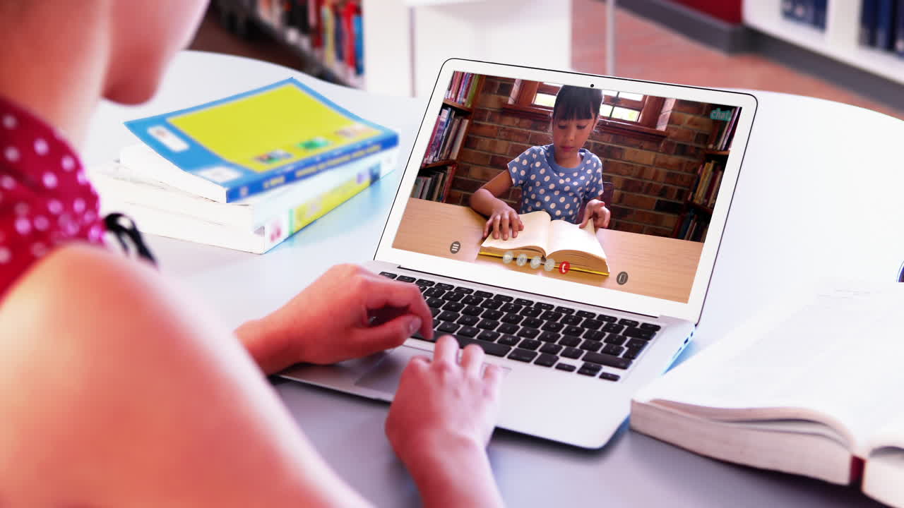 Profesora caucásica usando una laptop en videollamada con una estudiante.