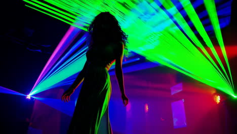 woman's silhouette dancing amidst vibrant laser lights in a club