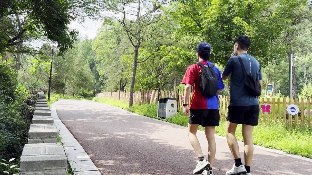 中国の公園を散歩する2人の友人が、趣のある木製の門が近くにある小道で楽しい時間を過ごしている