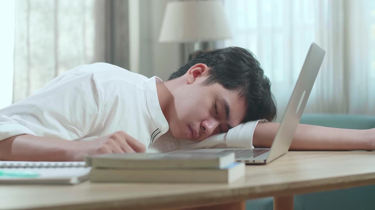Close Up Of Asian Man Student Sleeping While Using Computer To Study Online At Home