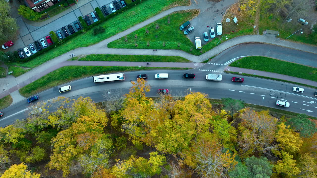 Aerial image of winding roads, parked cars, and vibrant fall trees forming a mixed landscape