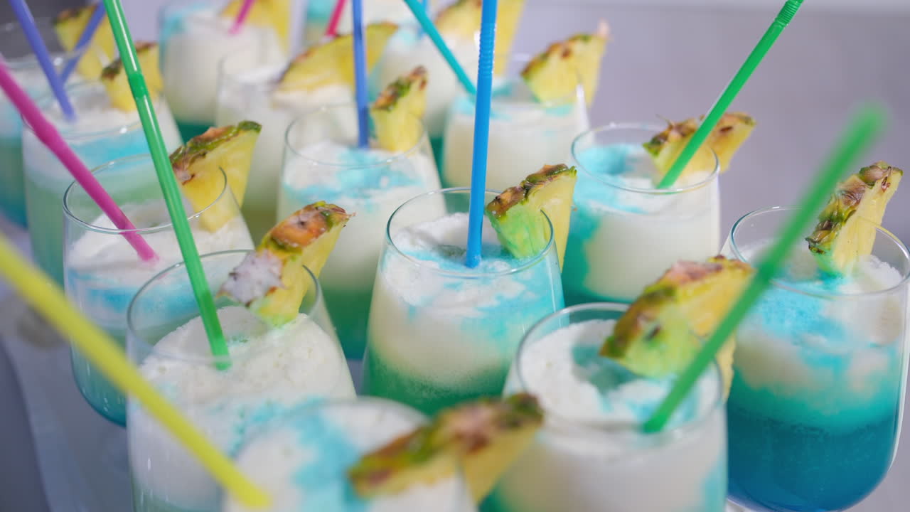 Refreshing tropical blue and white cocktails. Many glasses of pina colada cocktails with blue curacao and pineapple slices ready for a party