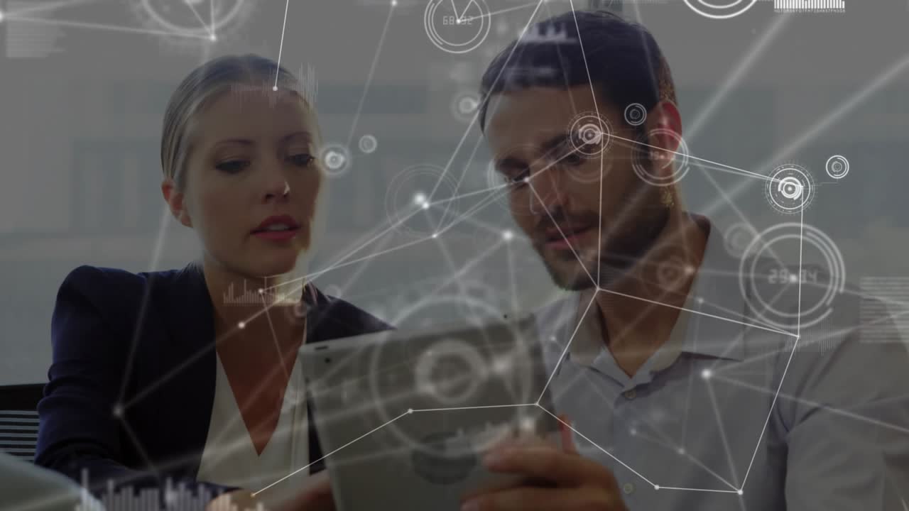 Woman tapping tablet man rotating it in business reviewing data with network charts over screen