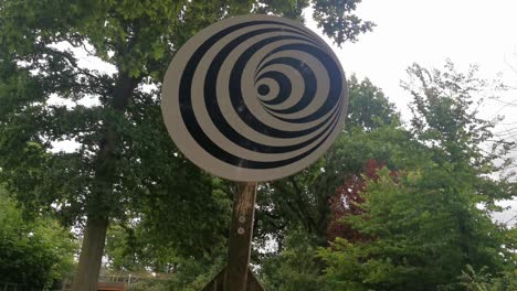 a spinning spiral optical illusion on a wooden pole in a park