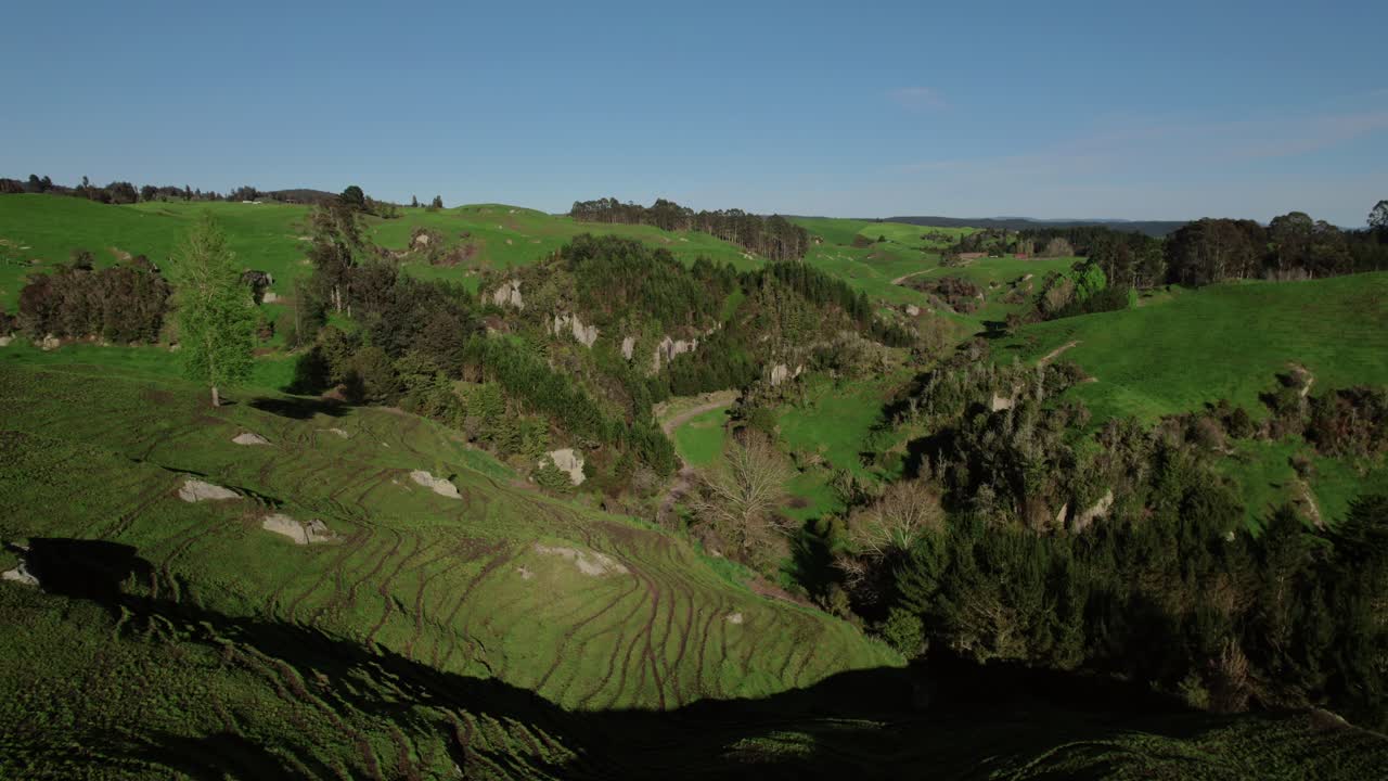 colinas verdes y terreno rocoso se encuentran con valles boscosos bajo un cielo azul claro.