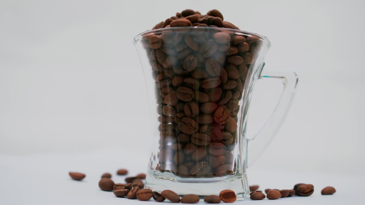 foto de estudio: granos de café dentro y alrededor de una taza de café alta y transparente con asa