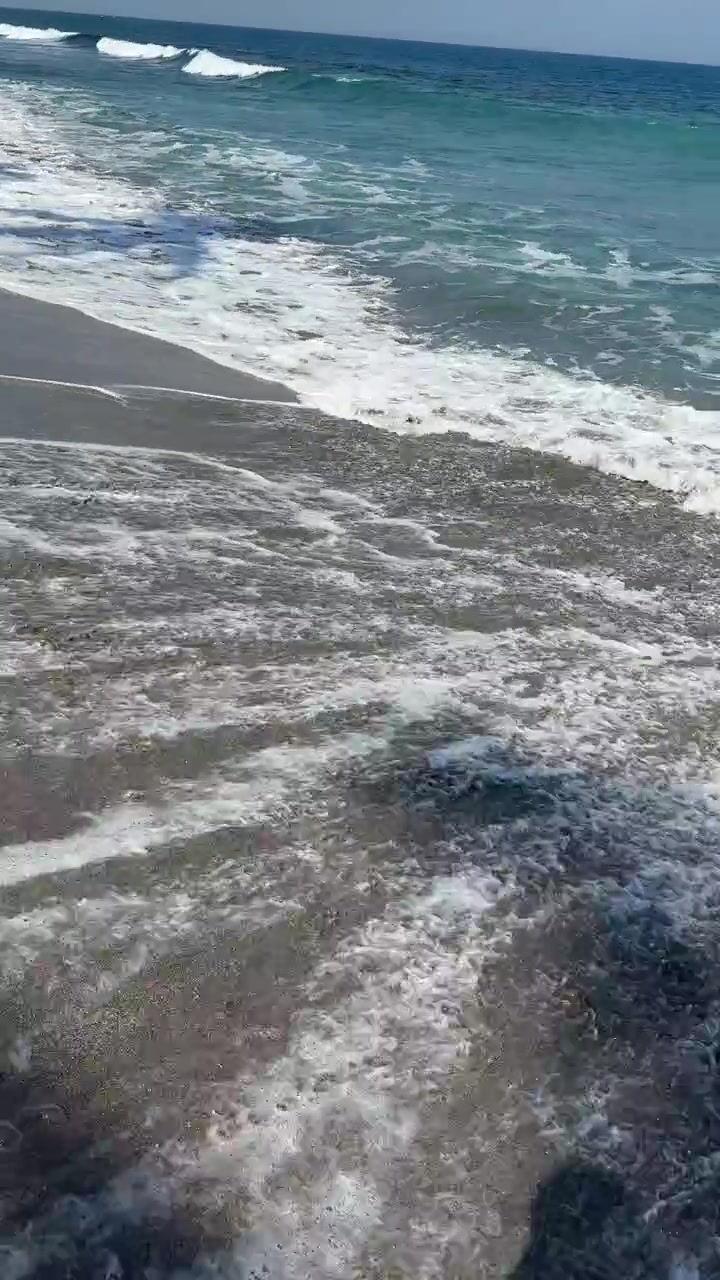 Onde dell'oceano che cancellano le impronte su una spiaggia sabbiosa