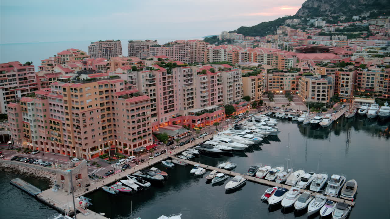 Aerial view of boats docked in the Port de Fontvieille with the skyline of Monaco on the background in the evening