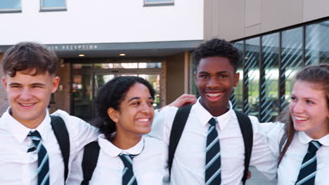 portrait of smiling male and female high school students wearing uniform outside college building