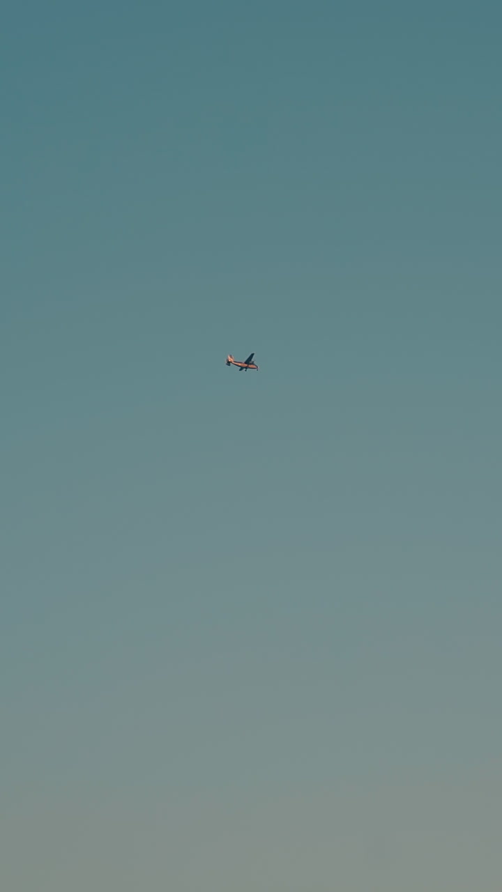 modern small airplane flies in boundless clear blue sky in nice autumn evening view from ground