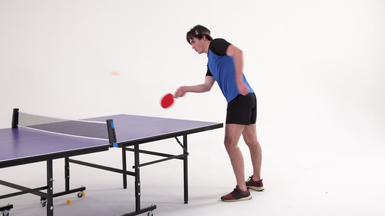Playing table tennis, man in blue shirt hitting ball on purple table