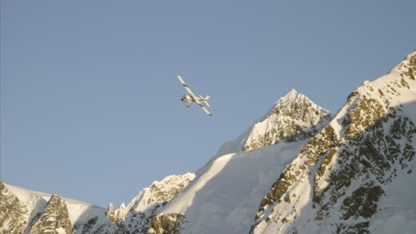 airplane flies low over snow covered mountain past moon