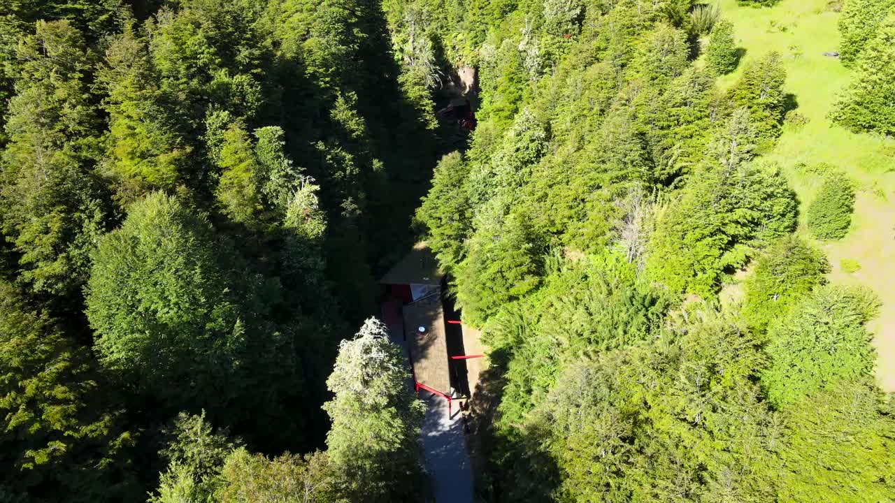 Aerial flying over Termas Geometricas hot spring complex hidden in ravine between dense green forest, Coñaripe, Chile