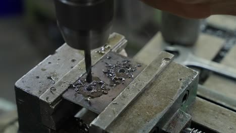 drill bit cuts through metal plate in vice during precision workshop work