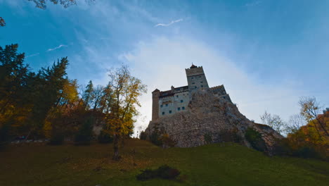 old dracula castle towering on the hill in brasov, romania. beautiful bright colorful trees surrounding the building.