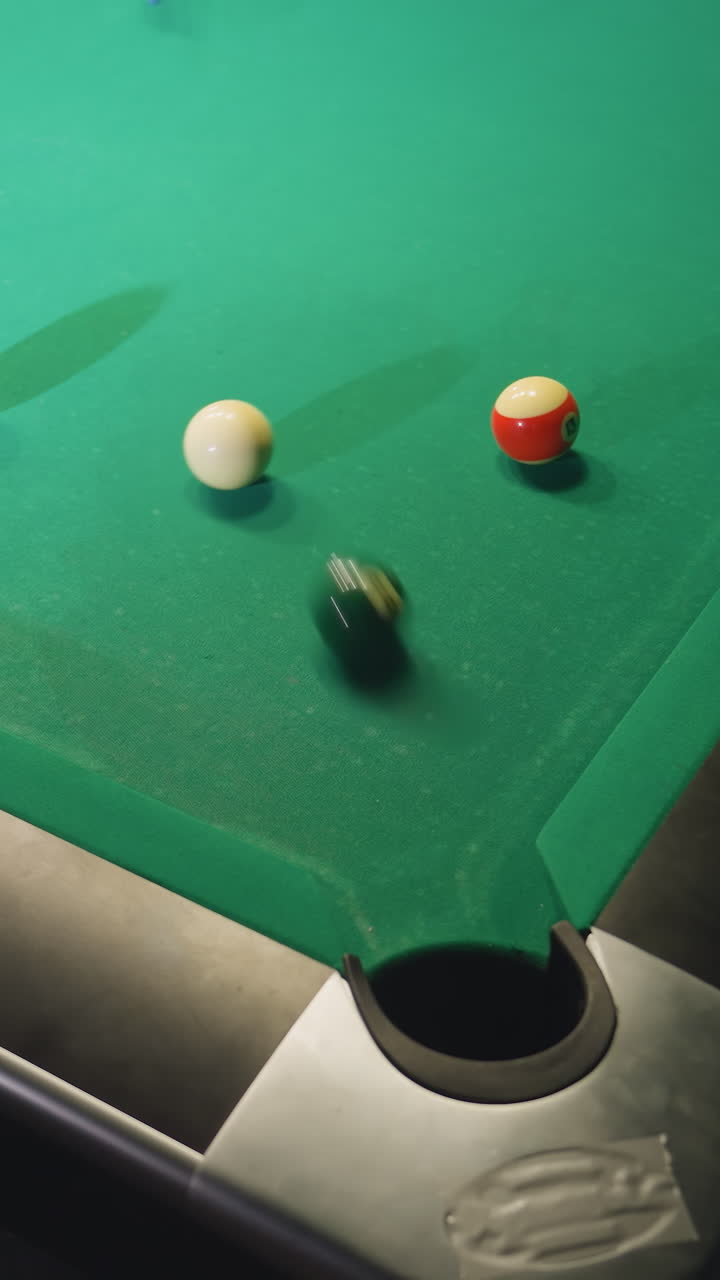 vista hacia arriba de la pelota de billar blanca rodando a través de la mesa de billar verde después de golpear la pelota verde y hundirse en el bolsillo. el borrón de movimiento captura la velocidad, la precisión e intensidad del juego