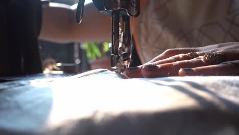 woman turn under and sew the edge of a cloth using a traditional manual sewing machine in agra city, india. - close up shot