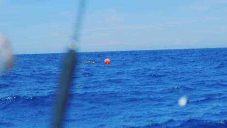 Close-up,-man-with-hand-on-fishing-rod,-rack-focus-to-orange-buoy-in-ocean