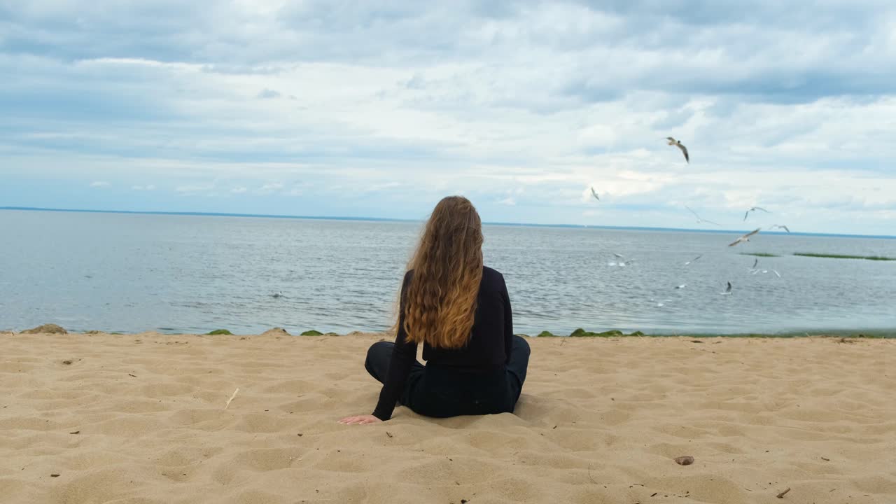 mujer sentada en la playa, contemplando el océano