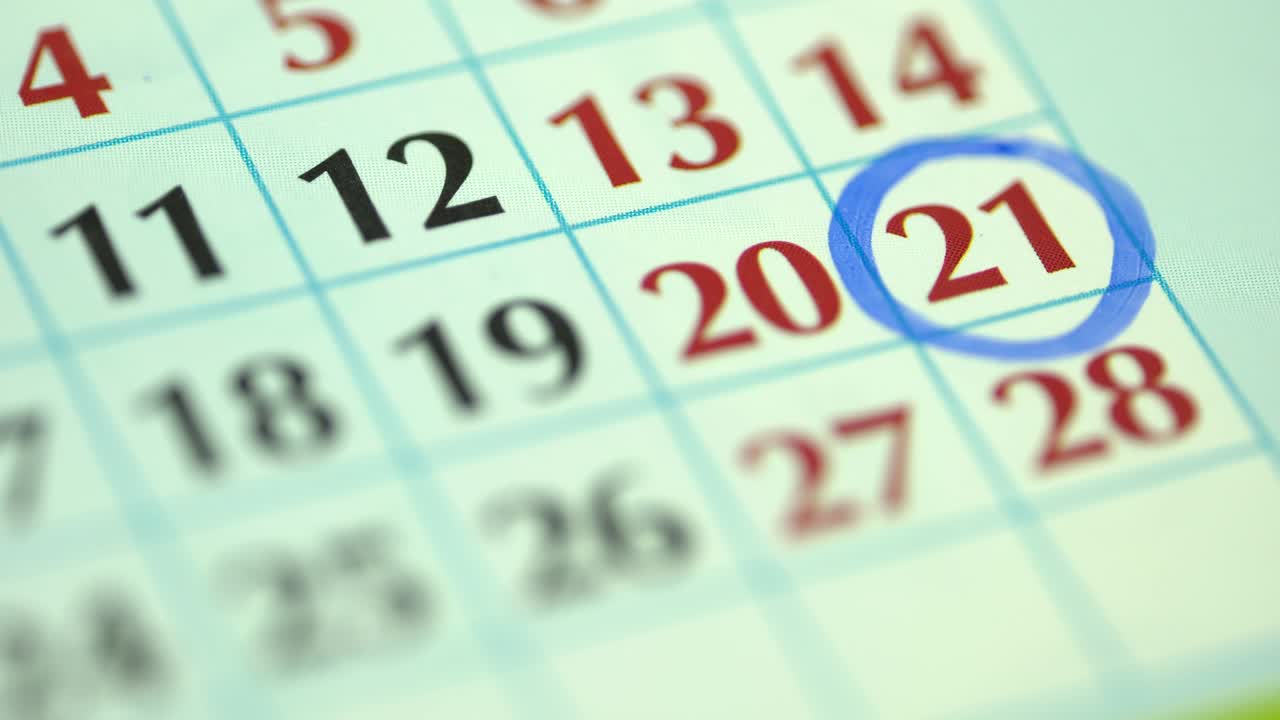 21st – twenty-first day of the month. The woman marks the calendar date with a blue marker. Business Wall Calendar Planner and Organizer