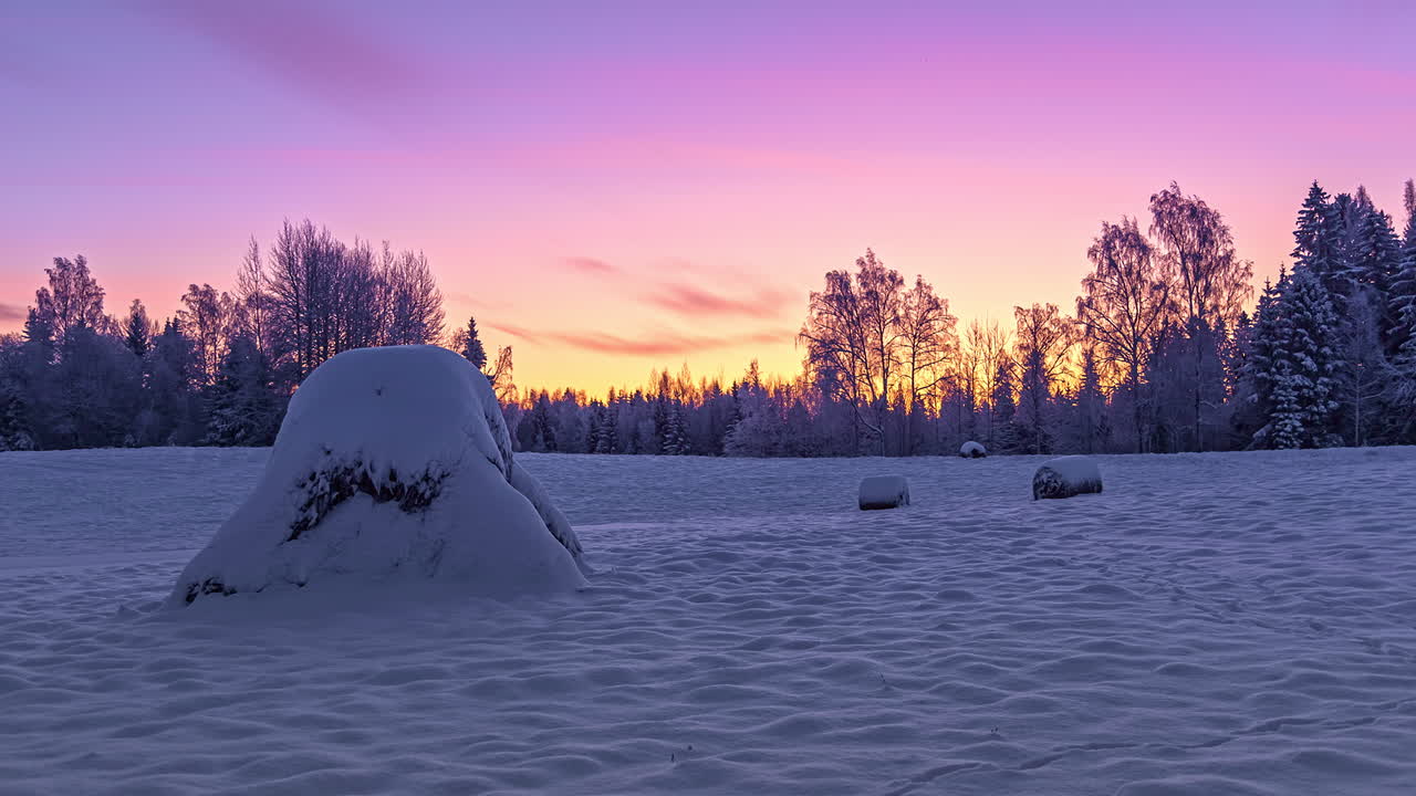 5K-aikaviivevideo lumisesta maisemasta, jossa liikkuvia pilviä värikkäällä taivaalla auringonlaskun aikaan talvella.