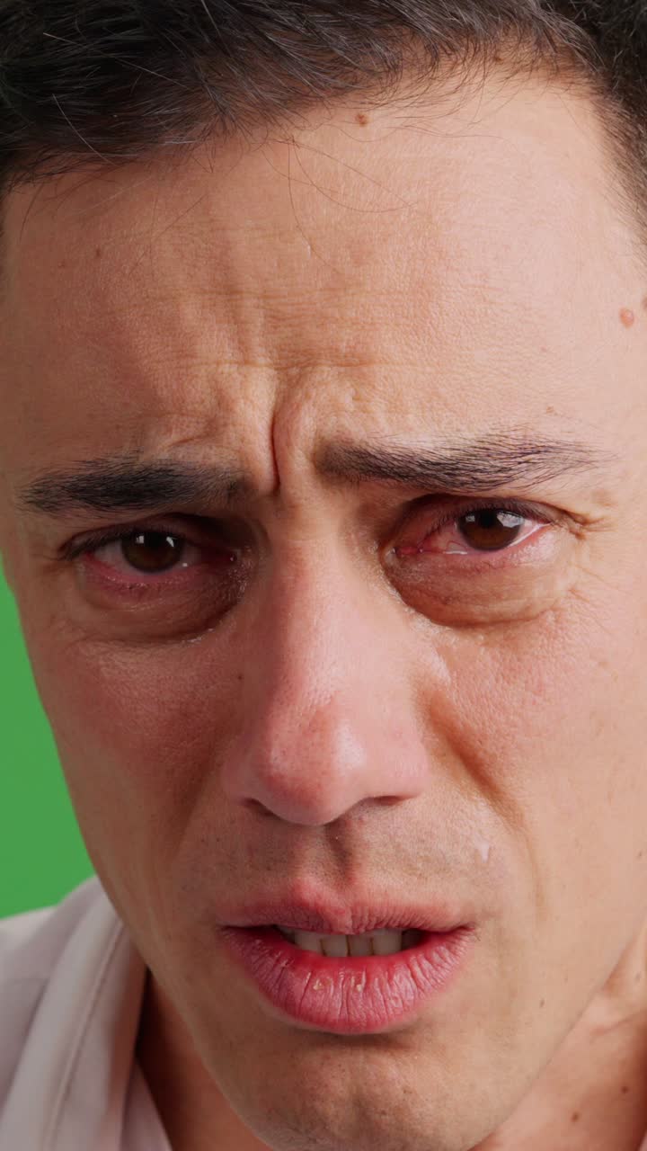 Sad man on green screen background struggling not to cry