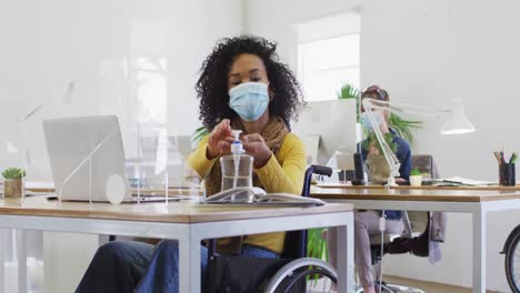 woman wearing face mask sanitizing her hands at office