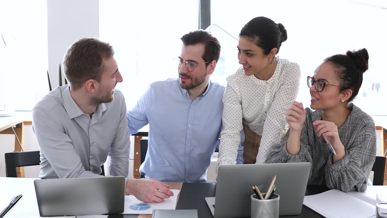 joven empleado masculino compartiendo una idea creativa con felices colegas diversos.