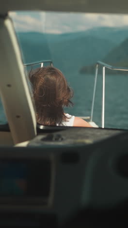 woman sits on deck while skipper controls motorboat in sea bay. lady enjoys water trip with professional yachtsman on summer vacation. seaside cruise