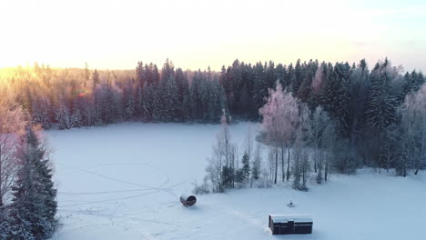 sunset over a frozen lake and sauna and cabin trailer in the winter countryside