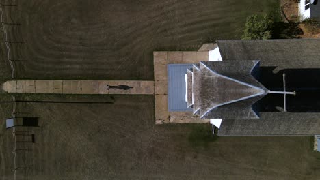 lonely person walking along narrow path towards old wooden country church in american prairie