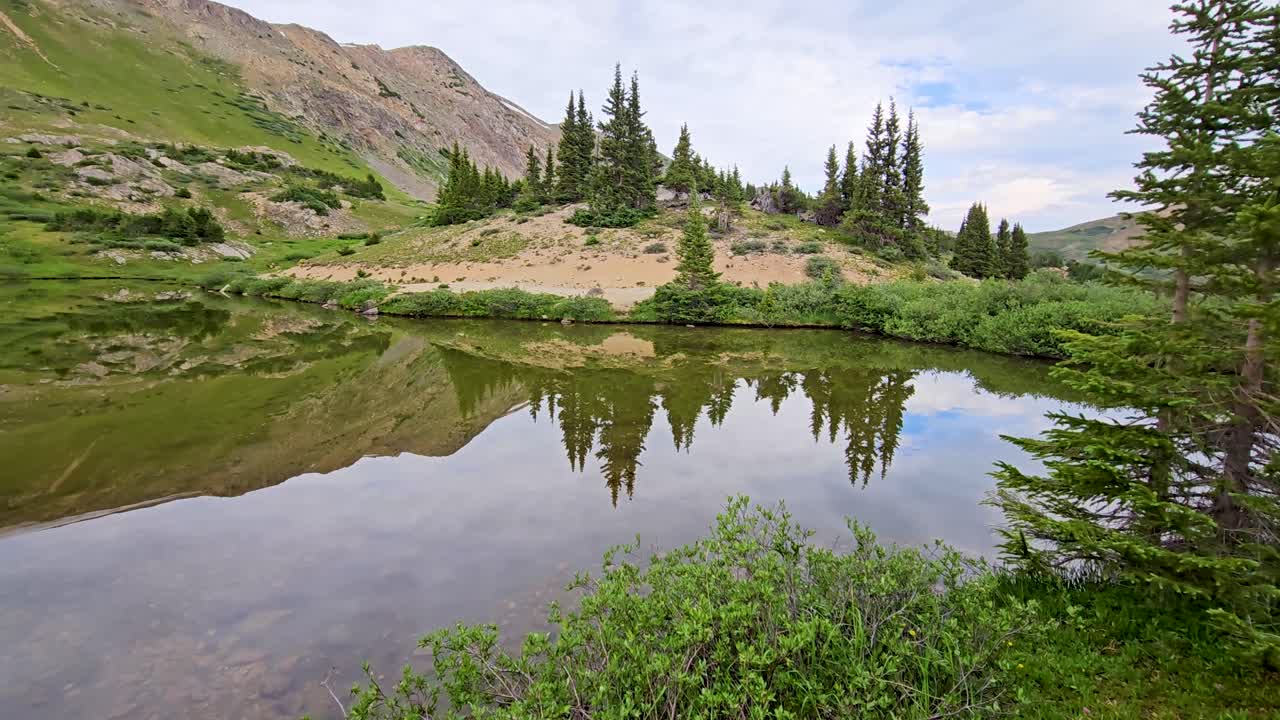 Handheld video of a scenic nature scene with a pond and mountains in Colorado.