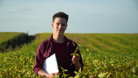 farmer with notepad looking at camera on soybean field