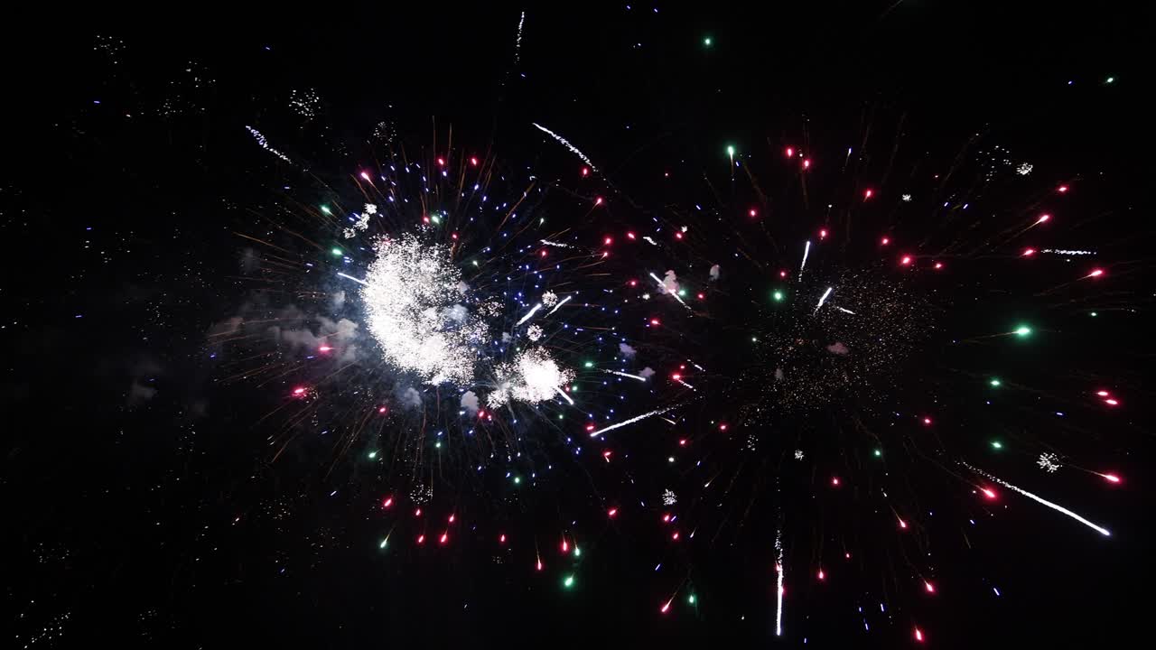 Loop continuo di lunga durata di un vero spettacolo astratto e colorato di fuochi d'artificio su un cielo con sfondo nero durante una festa nazionale, festa di Capodanno 2022.