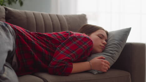Pretty tired young woman in casual garment sleeps on sofa