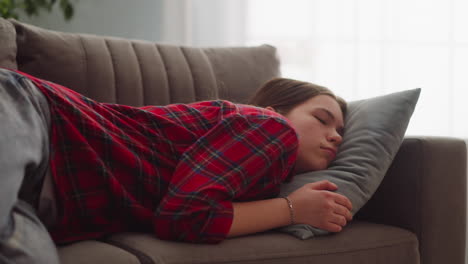 pretty tired young woman in casual garment sleeps on sofa