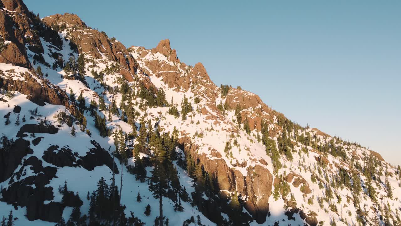 una foto de un dron ascendente de un pico nevado en las montañas olímpicas tomada desde las afueras del parque nacional