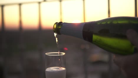 Zeitlupenaufnahme-Einer-Flasche-Prosecco,-Die-Bei-Sonnenuntergang-In-Ein-Glas-Gegossen-Wird