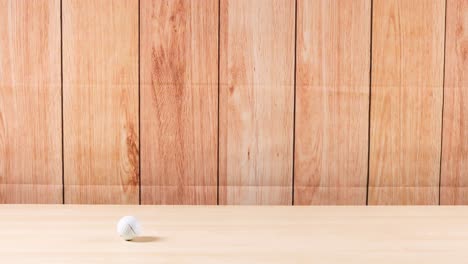 a golf ball rolls across a wooden table