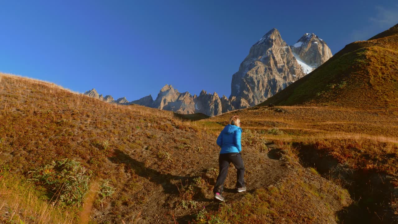 turista en guli pass caminando hacia mt ushba en mañana soleada, cáucaso, georgia