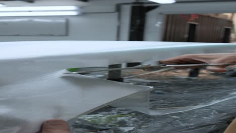 hombre irreconocible cortando película en la tabla de surf