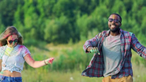 joven guapo y alegre bailando y divirtiéndose con una chica guapa en el festival holi afuera