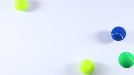 multiple tennis balls bouncing on a white surface