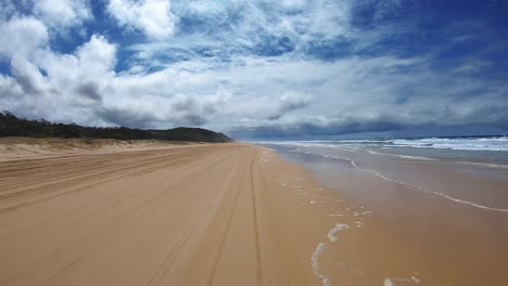 punto de vista de conducción mirando hacia atrás de una playa desierta de queensland bajo un cielo azul con bancos de nubes blancas - ideal para el reemplazo de la pantalla verde de la escena interior del automóvil