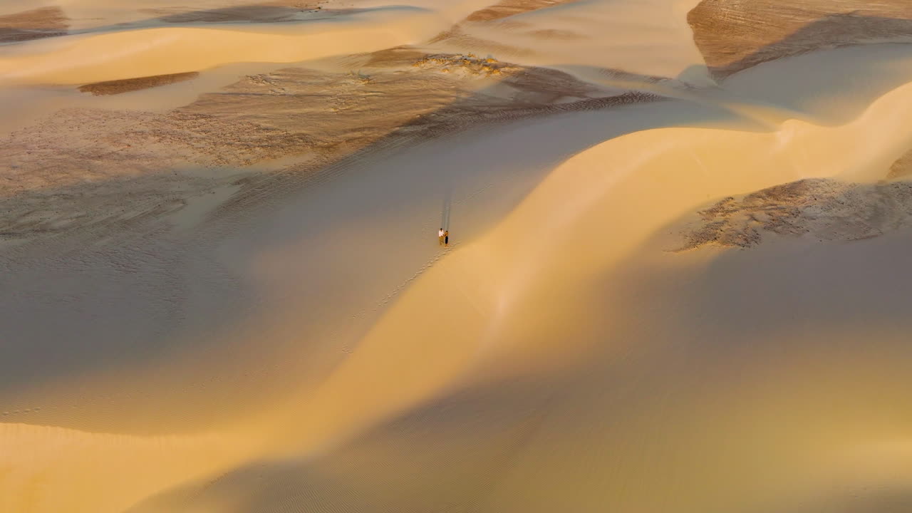 Above View Of A Couple Walking Across The Massive White Sand Of Zahek Sand Dunes In Da'ira, Yemen. Aerial Rotate Shot