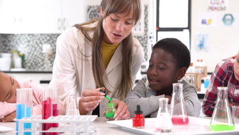 Demonstrating science experiment, teacher engaging students in school classroom