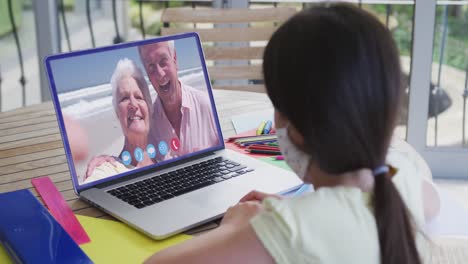 Caucasian-girl-on-laptop-video-chat-wearing-face-mask-at-home